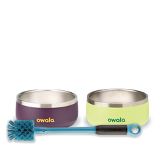 Owala Pet Bowl Bundle showing two stainless steel pet bowls — one deep purple with yellow Owala logo and one lime green with yellow Owala logo — alongside a teal-handled bottle brush with blue bristles