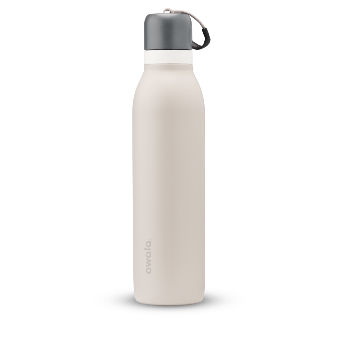FreeSip Twist 24oz in Rock On, soft cream-beige insulated water bottle with charcoal gray twist cap, white twist cap accent band, and tan carry string with dark gray grip